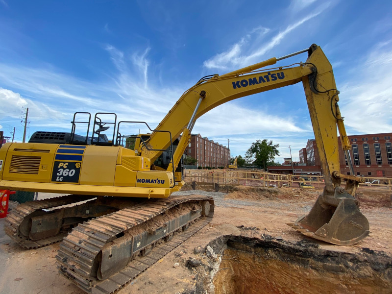 Commercial Construction site showing Excavator near partially dug hole.